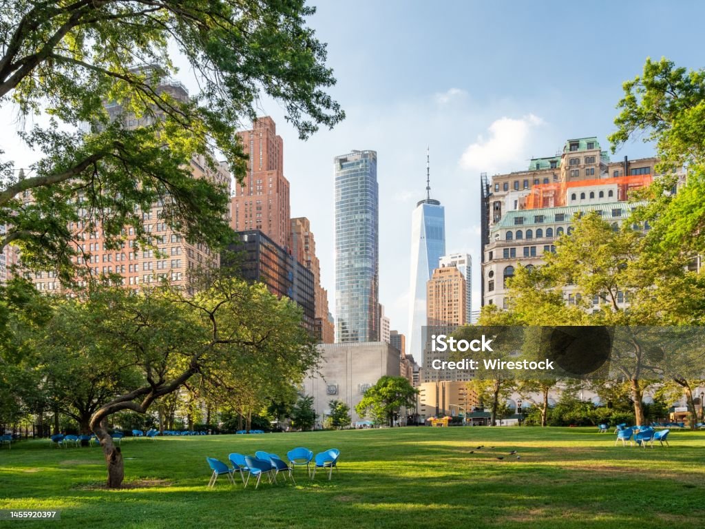A scenic view of empty blue chairs in green Battery Park in New York City, United States.
